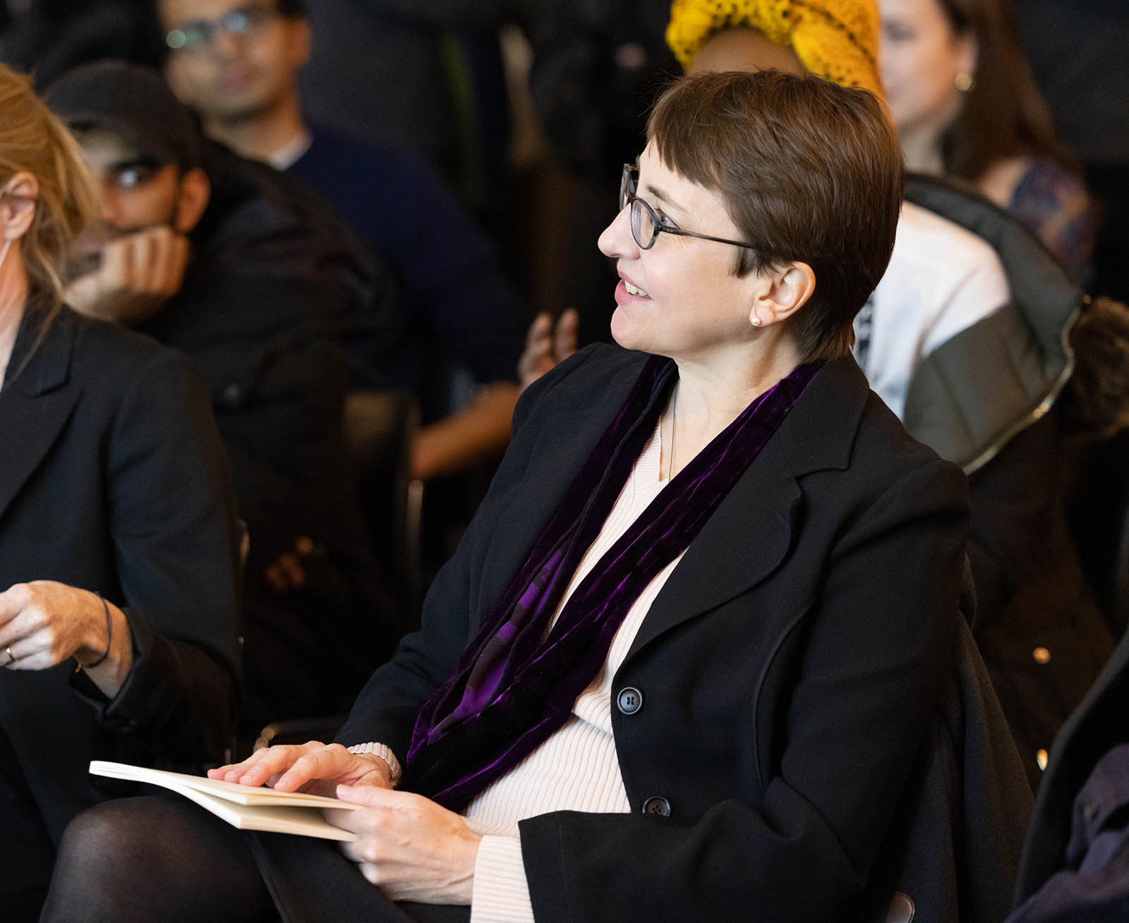 Erica Naginski sits in an audience looking off-camera to a presenter.