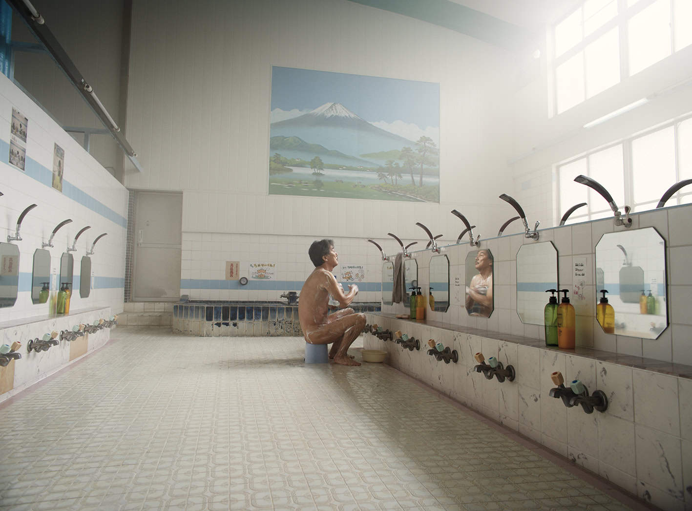 Image of a man washing himself while seated on a bucket in a restroom