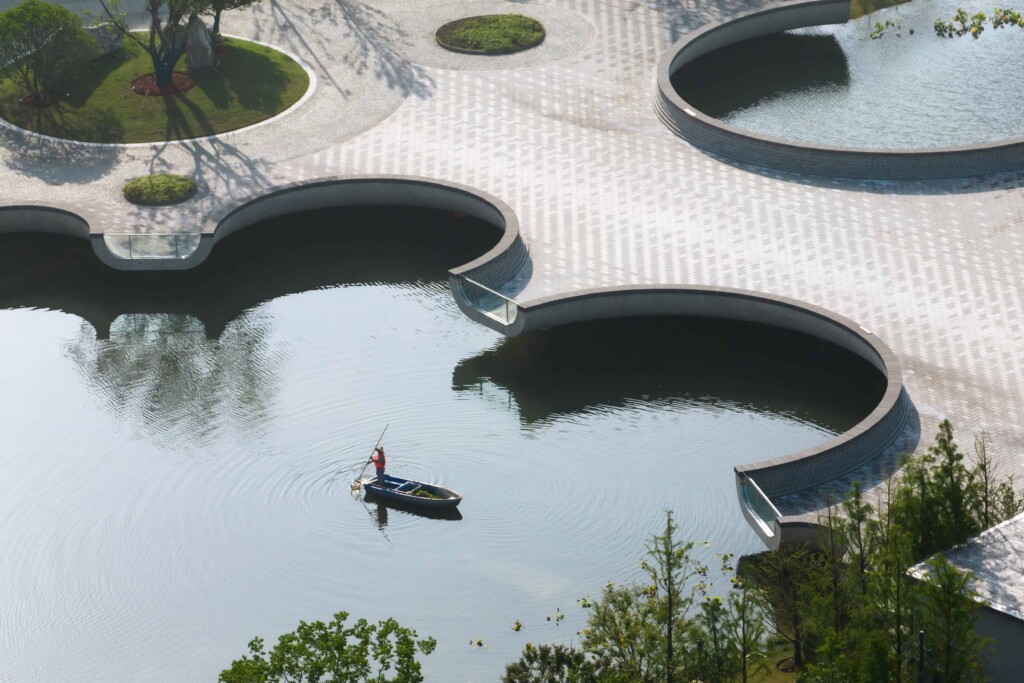 Photograph of man rowing next to the Moongate Bridge in Shanghai