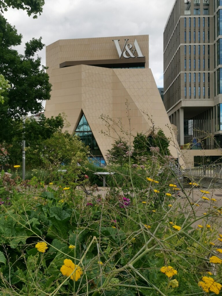 Photograph of beige building surrounded by flowers