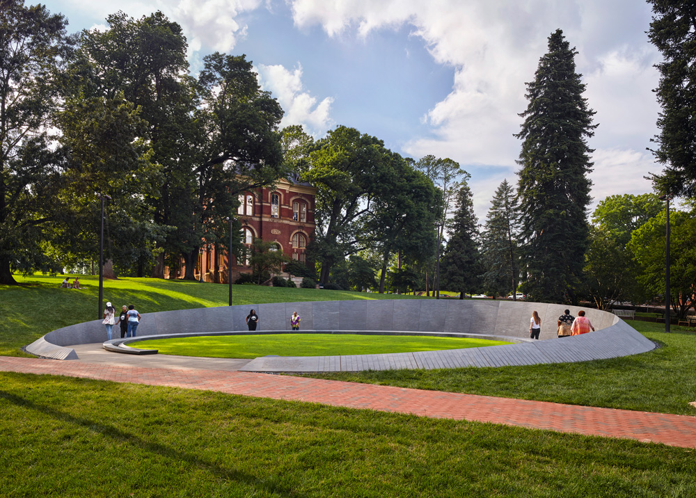 Photo of Memorial to Enslaved Laborers, University of Virginia, showing group of people near a curved stone structure.