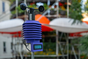 A purple climate sensor appears in the foreground with the Polinature structure by Belinda tato in the background.