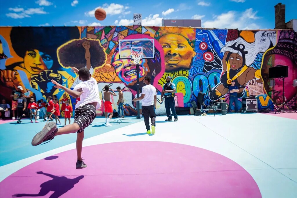 Children playing basketball in court with vibrant murals