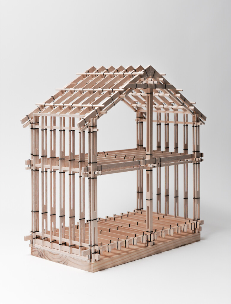 Architectural model of a house-shaped structure built with slats of wood joined to each other with straps.